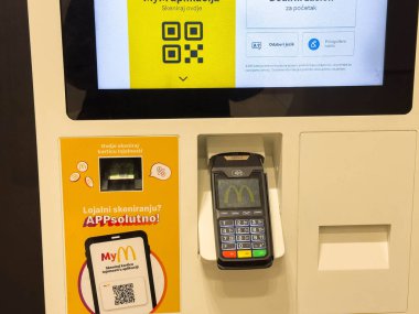Zagreb, Hırvatistan - 17 Aralık 2025: Ödeme terminali ve menü ve kolay sipariş vermenin QR kodlu parlak ekranlı fast food restoranında self-servis büfesi