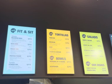 Zagreb, Hırvatistan - 17 Aralık 2025: Canlı menü panolarında çağdaş bir restoranda çeşitli yemekler sergileniyor, salatalar, tortillalar ve cazip renklerde kaseler vurgulanıyor