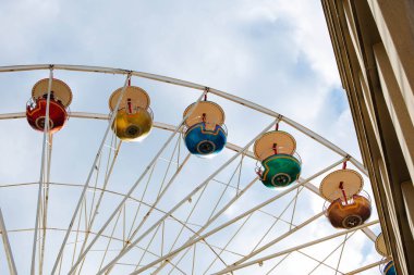 Binanın yakınında bulutlu gökyüzüne karşı renkli dönme dolap.