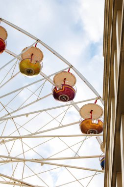 Binanın yakınında açık gökyüzüne karşı renkli dönme dolap.