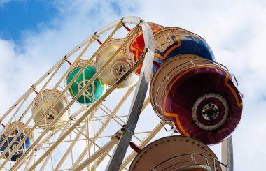 Güneşli bir günde mavi gökyüzüne karşı renkli dönme dolap.