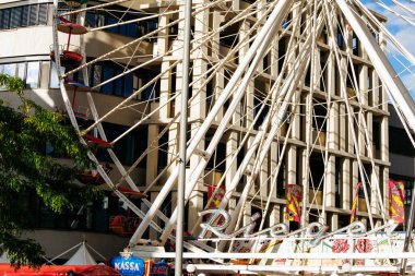 Villach, Avusturya - 29 Temmuz 2025: Dönme dolap belirgin bir şekilde arka planda renkli dekorasyon ve binalar ile gösterilir, bir panayırın canlı ruhunu yansıtır