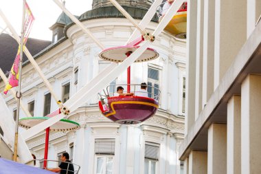 Villach, Avusturya - 29 Temmuz 2025: Festivalde tarihi bina zeminli canlı gondollar içeren dönme dolap hareketli ve neşeli bir ortam yaratıyor