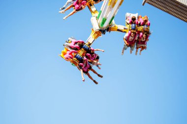 Villach, Avusturya - 29 Temmuz 2025: Eğlence gezisinde havada asılı duran neşeli sürücüler yaz şenliklerinin ve canlı atmosferin heyecanını yakalıyorlar