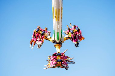 Villach, Avusturya - 29 Temmuz 2025: Swing gezisinde parlak mavi bir gökyüzü altında coşkulu bir festivalde heyecan ve heyecan yaşayan neşeli sürücüler yer alıyor