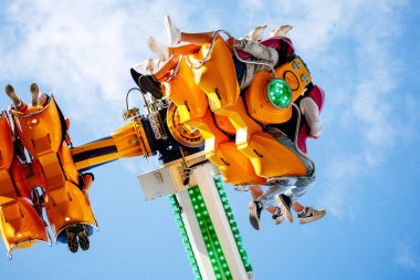 Villach, Avusturya - 29 Temmuz 2025: Eğlence parkı gezisi, açık mavi gökyüzü altında heyecan verici deneyimin tadını çıkaran sürücüleri içeriyor