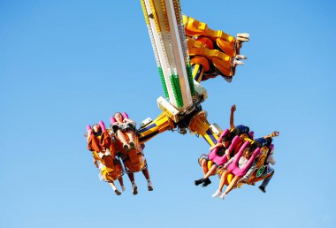 Villach, Avusturya - 29 Temmuz 2025: Lunapark gezisi, yaz kutlamaları sırasında parlak mavi gökyüzü altında heyecan ve heyecan yaşayan neşeli binicileri barındırır