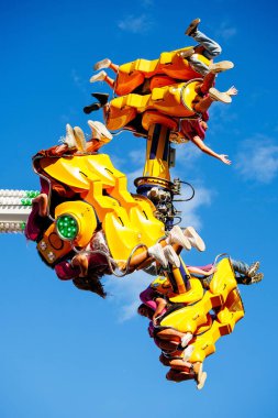 Villach, Avusturya - 29 Temmuz 2025: Heyecanlı sürücüler, canlı mavi gökyüzüne karşı baş aşağı asılı, festivalde heyecan verici bir eğlence turu deneyimlediler