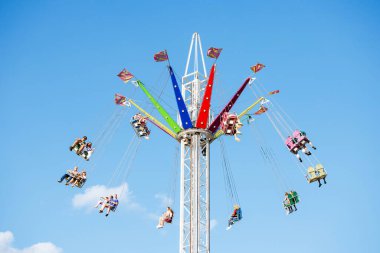 Villach, Avusturya - 29 Temmuz 2025: Renkli salıncak gezisi, yaz şenliklerinin ruhunu somutlaştıran, mavi gökyüzüne doğru yükselen neşeli binicileri içerir.