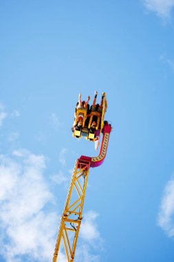 Villach, Avusturya - 29 Temmuz 2025: Eğlence gezisi heyacan verici sürücüler, mavi bir gökyüzü ve tüylü bulutlarla çevrelenmiş, festival ruhunu yakalıyorlar