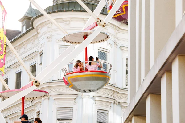 Villach, Avusturya - 29 Temmuz 2025: Festivalde dönme dolap, tarihi mimariye karşı renkli gondollar, neşeli bir atmosfer yaratıyor