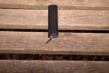 Kırsal ahşap bankta siyah deri gözlük kutusu..