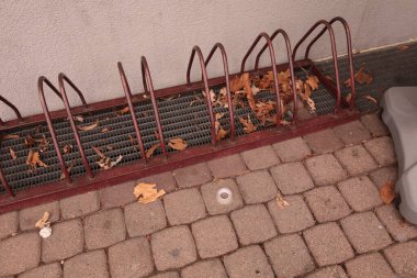 Boş bisiklet parkı, tuğla kaldırımda düşmüş yapraklarla..