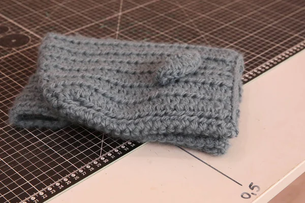 Mavi örülmüş yün eldivenler ve şebeke kesme paspası..