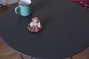 Teal kupa ve küçük bebek rahat bir ortamda siyah yuvarlak masa üzerinde.