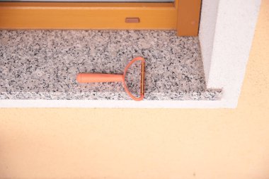 Granit pervazda şeftali saplı plastik pencere temizleyicisi.