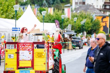 Velden, Avusturya - 30 Ağustos 2025: Neşe dolu kadınlarla dolu bir festival sahnesi, dekore edilmiş bir traktörle, toplum ruhunu ve Oldtimer Festivali 'nde canlı bir atmosferi kutluyor