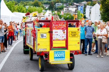 Velden, Avusturya - 30 Ağustos 2025: Kirchtag festivalinde renkli geçit töreni şamandırası, neşeli katılımcılar ve canlı dekorasyonlar içeriyor ve canlı bir sokak atmosferi yaratıyor