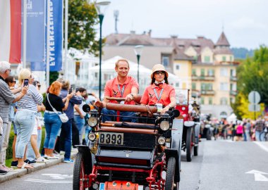 Velden, Avusturya - 30 Ağustos 2025: Antika araba meraklıları, Oldtimer Festivali 'nde canlı bir sokak atmosferi ve coşkulu izleyicilerle çevrili klasik bir otomobil kullanıyorlar