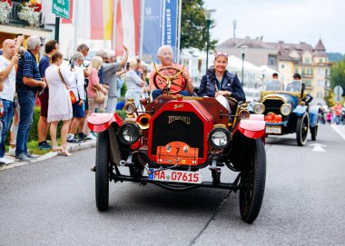 Velden, Avusturya - 30 Ağustos 2025: Klasik araba severler, coşkulu kalabalık ve büyüleyici manzaralarla çevrili Oldtimer Festivali 'nde klasik araba sürmenin keyfini çıkarıyorlar