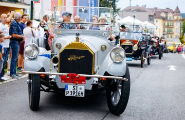 Velden, Avusturya - 30 Ağustos 2025: Vintage otomobil geçidi, yaşlı festival atmosferinin keyfini çıkaran heyecanlı izleyicilerle çevrili 1920 'lerden kalma güzel bir Pierce-Arrow' u ön plana çıkarıyor