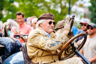 Velden, Avusturya - 30 Ağustos 2025: Klasik araba sevdalısı, etkinliğin keyfini çıkaran coşkulu kalabalıkla çevrili Oldtimer Festivali 'nde klasik araç kullanıyor