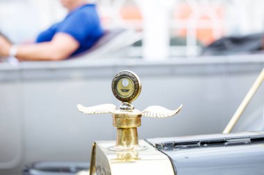 Velden, Avusturya - 30 Ağustos 2025: Klasik otomobillerle çevrili bir Eski Zaman Festivali 'nde kanatlı ayrıntıları olan klasik bir arabanın kaput süslemesi