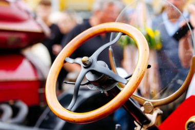 Velden, Avusturya - 30 Ağustos 2025: Klasik arabanın ahşap direksiyonu Oldtimer Festivali 'nde arka planda bulanık kalabalıkla, nostalji ve klasik otomobillere duyulan tutkuyu çağrıştırdı