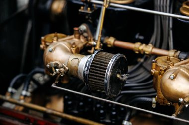 Velden, Avusturya - 30 Ağustos 2025: Klasik otomotiv mühendisliğinin güzelliğini vurgulayan antika otomobil motorunun yakın çekimi pirinç bileşenleri ve hava filtresi ortaya çıkardı