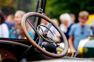 Velden, Avusturya - 30 Ağustos 2025: Oldtimer Festivali 'nde klasik direksiyon simidine yakın plan, arka planda bulanık kalabalık, işçilik ve nostalji vurgulanıyor
