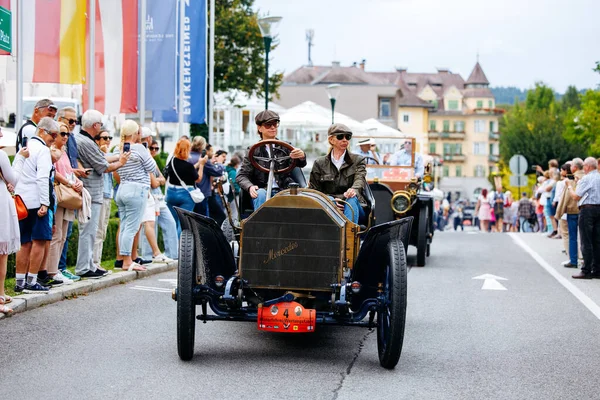 Velden, Avusturya - 30 Ağustos 2025: Klasik araba meraklıları Oldtimer Festivali 'nde antika bir otomobil kullanıyor, izleyiciler canlı atmosferin keyfini çıkarıyor