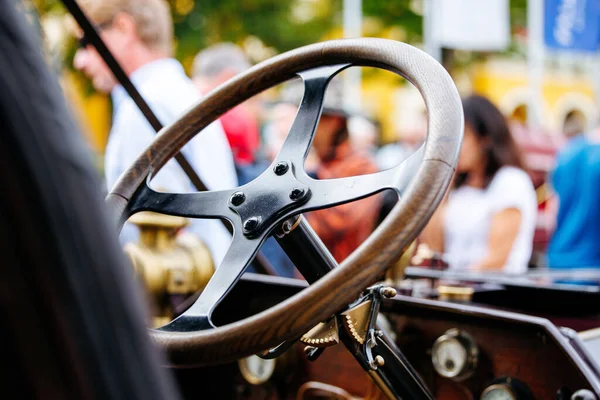 Velden, Avusturya - 30 Ağustos 2025: Eski Çarklar Festivali 'nde eski araba direksiyonu vurgulandı, arka planda hareketli bir kalabalık var, otomotiv mirasını kutluyorlar