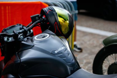 Velden, Avusturya - 30 Ağustos 2025: Suzuki motosikleti, şehir motosiklet kültürü ve tasarım estetiğini ön plana çıkaran şık bir siyah tank ve yansıtıcı miğfer içeriyor