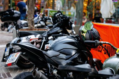 Velden, Avusturya - 30 Ağustos 2025: Siyah motosiklet turuncu pankartın yanında duruyor, kentsel çevre ve motosiklet meraklılarını vurguluyor