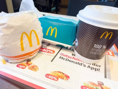 Villach, Avusturya - 11 Ocak 2026: Hamburger, patates kızartması ve kahve de dahil olmak üzere McDonald 's' ın gıda ürünleri, canlı bir yemek atmosferi için promosyon teklifleriyle dolu bir masada.