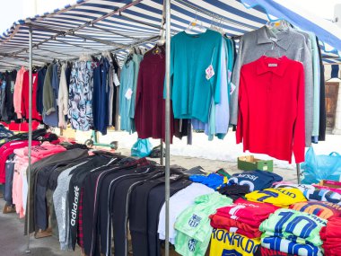 Villach, Avusturya - 12 Ocak 2026: Canlı bir alışveriş deneyimi yaratan, kazak ve forma gibi renkli giysi ürünleriyle dolu canlı bir pazar tezgahı