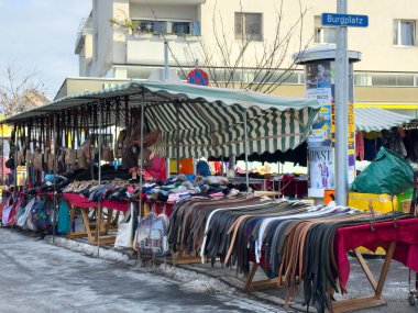 Villach, Avusturya - 12 Ocak 2026: Burgplatz 'da açık hava pazarı çeşitli giyim ve aksesuarları sergiliyor, müşterileri yerel zanaatkarlığı ve hareketli toplum atmosferini keşfetmeye davet ediyor