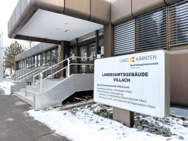 Villach, Avusturya - 19 Ocak 2026: Villach 'taki hükümet binası girişi karla kaplı basamaklar, modern mimari ve ulaşılabilirlik için açık tabela içeriyor