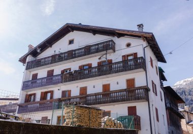 Cortina, İtalya - 27 Ocak 2026: Dolomitler 'de açık mavi bir gökyüzünün altında bulunan ahşap balkonların ve odun yığınlarının yer aldığı Alp tarzı bina
