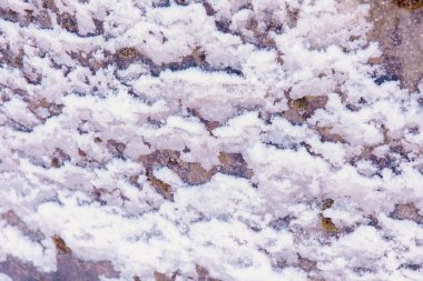 Ayrıntılı dokuya sahip karla kaplı kaya yüzeyine yakın çekim.