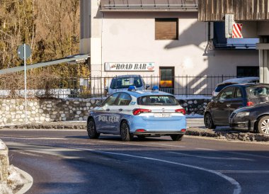 Cortina, İtalya - 27 Ocak 2026: POLIZIA etiketli polis aracı, Dolomitlerde görülebilen ve kış manzarası ile çevrili kavisli bir yolda ilerliyor