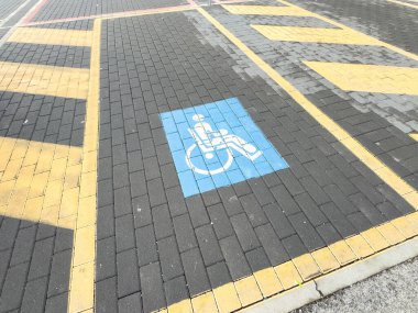 Tuğla kaldırımında mavi tekerlekli sandalye sembolü olan ulaşılabilir park yeri.