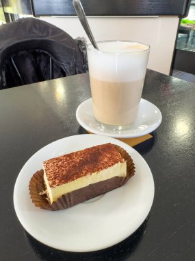 Kafe masasında tiramisu keki ve kapuçino.