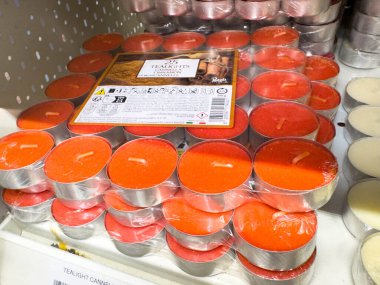 Ponte Nelle Alpi, İtalya - 27 Ocak 2026: Alüminyum konteynırlardaki kırmızı mum yakındaki bir rafta yerleştirilmiş ek beyaz mumlar