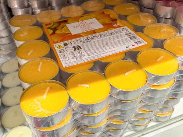 Ponte Nelle Alpi, İtalya - 27 Ocak 2026: Plastik bir kaptaki sarı çay ışığı mumları, arka planda birden fazla mum rengi sergilenen bir rafta sergilenmektedir