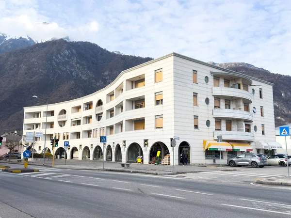 Ponte Nelle Alpi, İtalya - 27 Ocak 2026: Eğimli tasarım ve balkonların yer aldığı çağdaş konut yapısı, yakınlarındaki dükkanlar ve trafik işaretleriyle dağlık bir bölgede yer almaktadır.