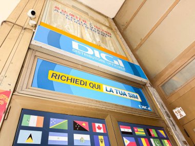 Venedik, İtalya - 17 Şubat 2026: SIM kart hizmetleri için bir tabela ve giriş kapısında uluslararası bayraklar sergilenen mağaza