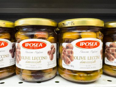 Venedik, İtalya - 14 Şubat 2026: Şeffaf cam camlarda çeşitli renkli zeytinlerin sergilendiği bir market rafında düzenlenen Iposea Leccino zeytinleri kavanozları