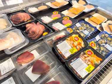 Venedik, İtalya - 14 Şubat 2026: Ahtapot ve balık filetoları da dahil olmak üzere çeşitli plastik ambalaj ürünleri, bir bakkal soğutma ünitesinde düzenlenmiştir.