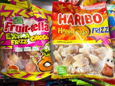 Venedik, İtalya - 14 Şubat 2026: Fruitella Extra Frizz ve Haribo Happy Cola Frizummy şeker paketleri bir rafta parlak renkler ve farklı markalar sergileniyor